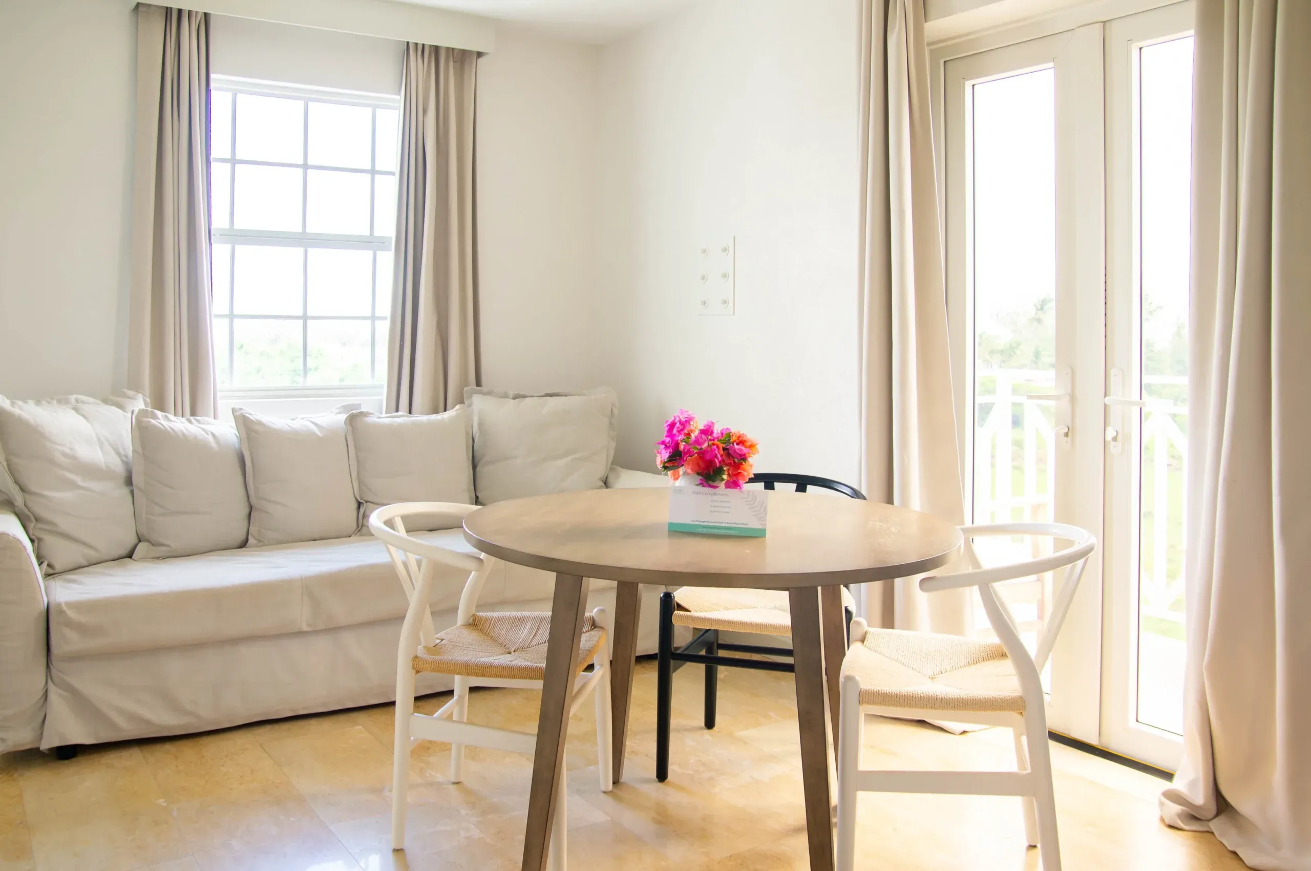 The sitting room of the King Ocean view, complete with a white couch, and small table surrounded by white bamboo chairs.