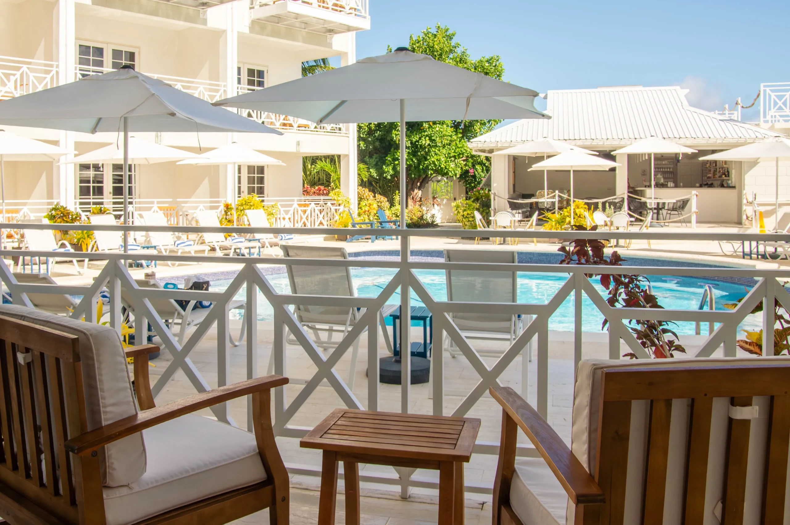 Swimming pool area at South Point Hotel with lounge chairs, white umbrellas, and a view of the surrounding building and pool bar.