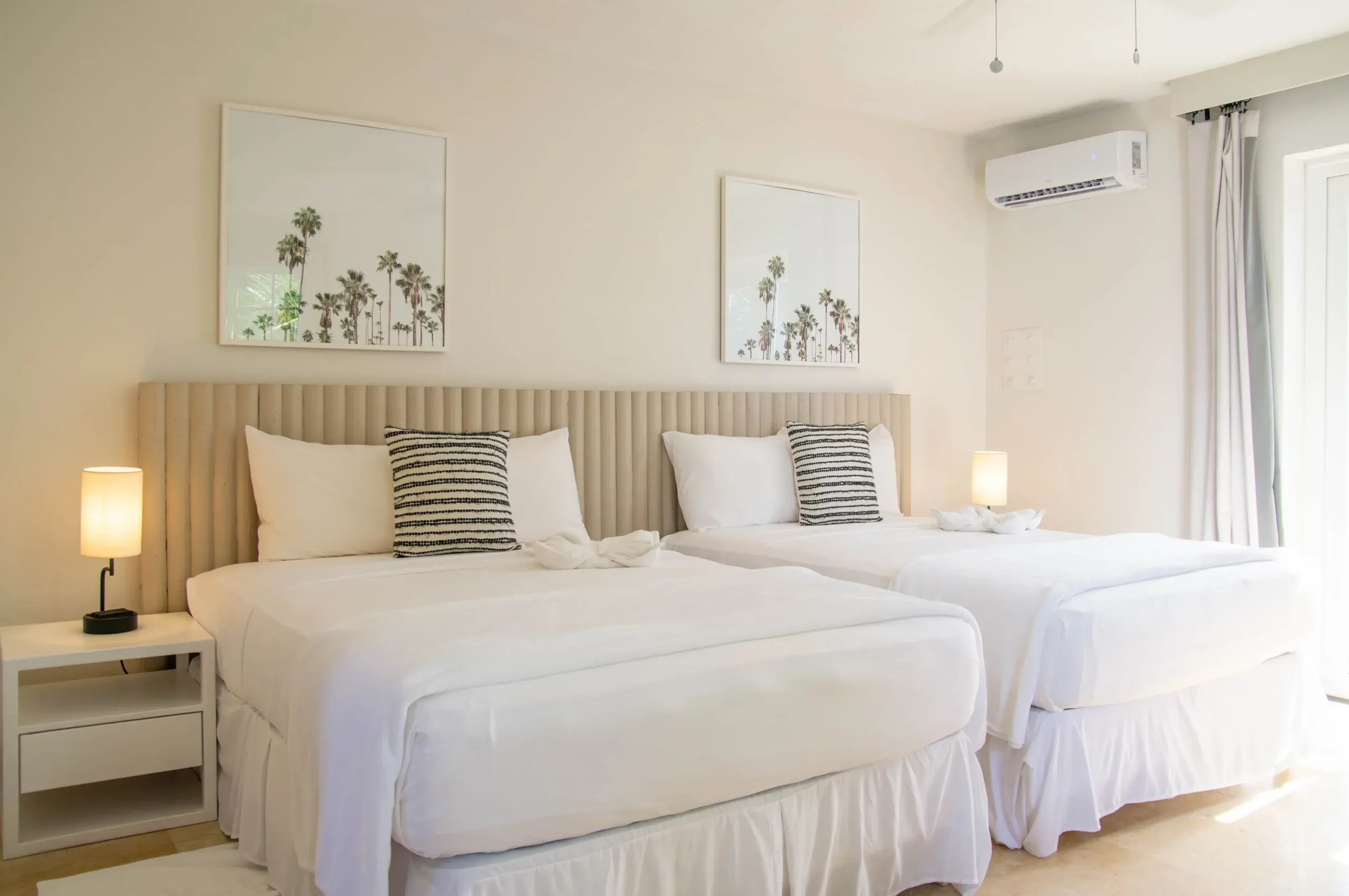 Two beds in the pool view two double suite at South Point Hotel. Tropical decor is visible, accenting the cream white colouring of the room's interior.